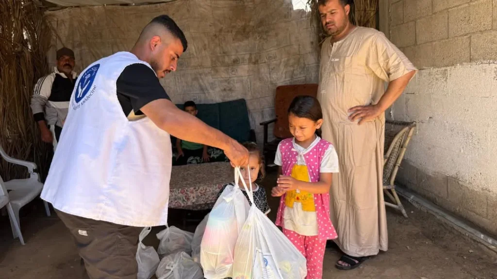 Aid worker giving supplies to two girls