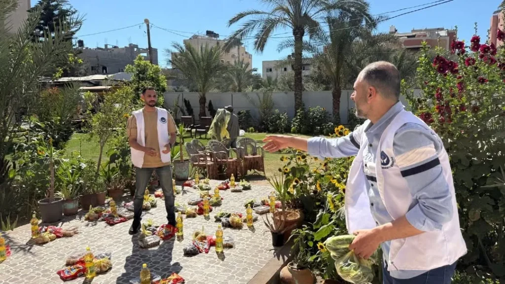 Deux hommes distribuent des vivres dans un jardin