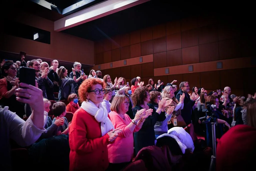 Public debout applaudissant dans un auditorium.