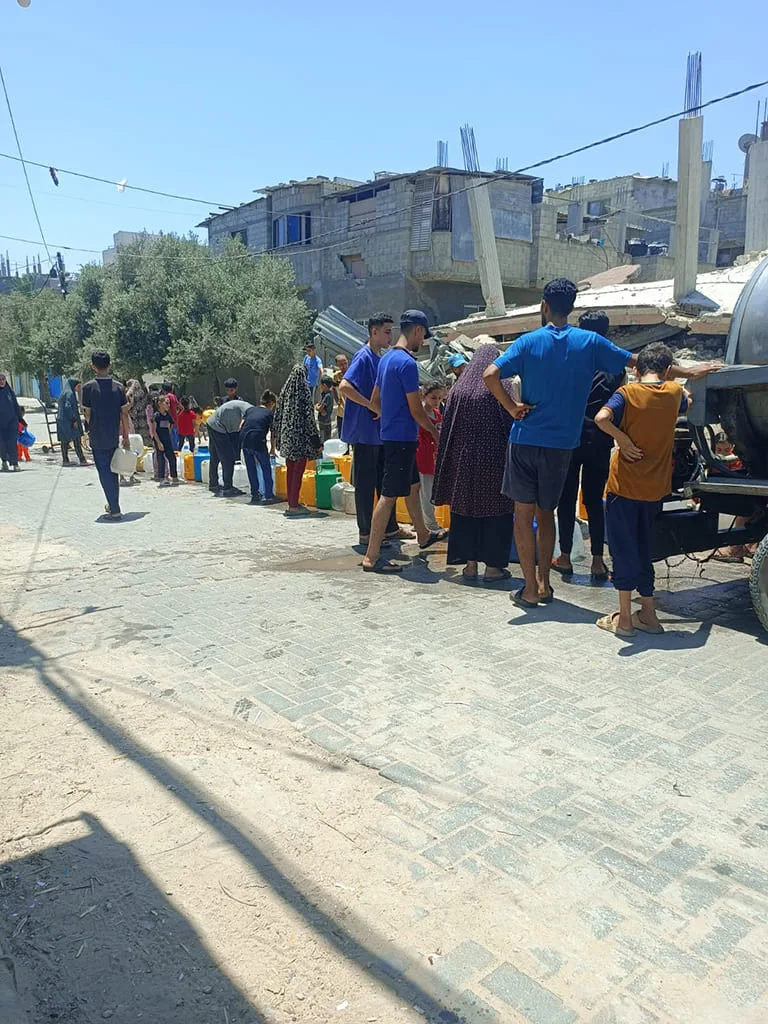 Personnes collectant de l’eau dans une rue.