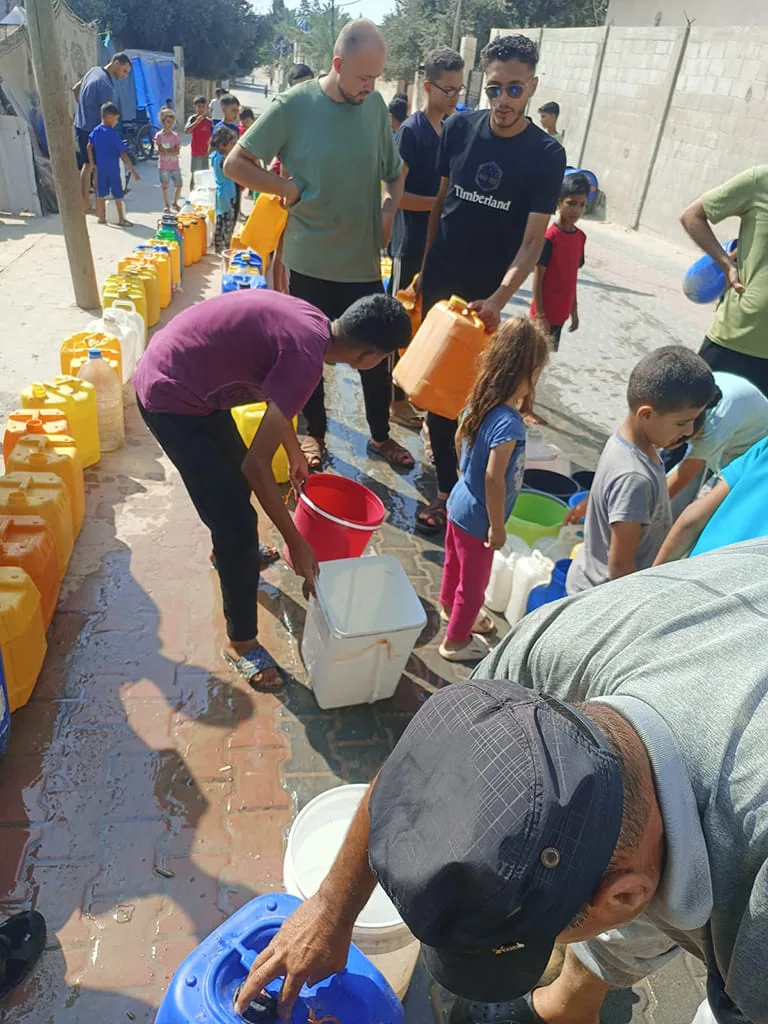 Personnes collectent de l’eau dans des bidons.