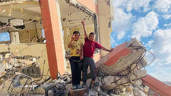 Enfants souriant sur des débris de bâtiment.