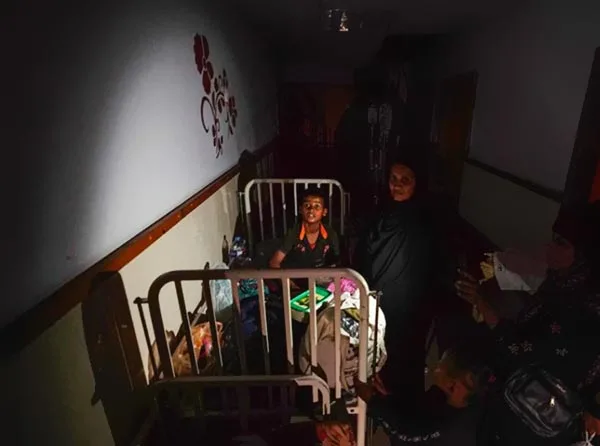Enfant dans lit d'hôpital sombre avec visiteurs.