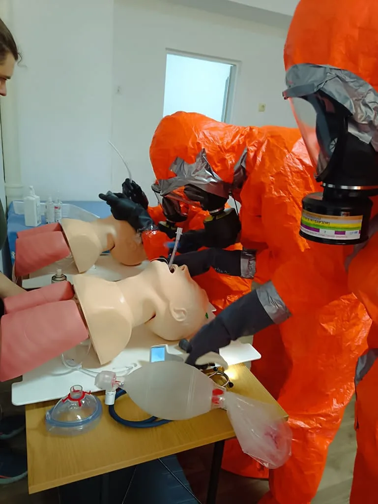 Simulation médicale avec mannequin et combinaisons de protection.