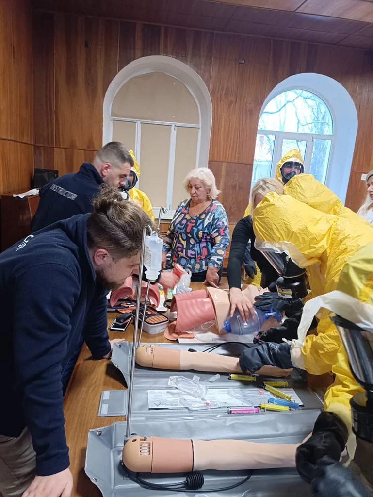 Entraînement médical avec mannequins et combinaisons jaunes.