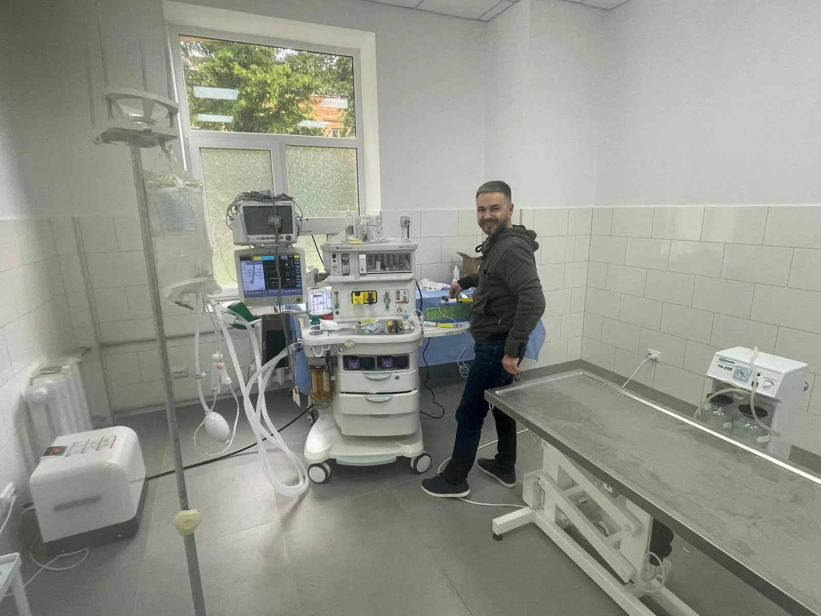 Salle d’hôpital avec équipements médicaux modernes et homme souriant.