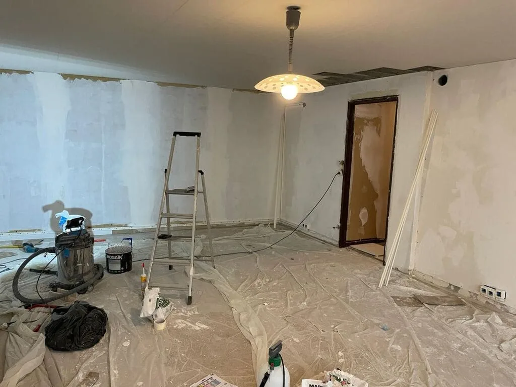 Salle en rénovation, équipement de peinture visible.