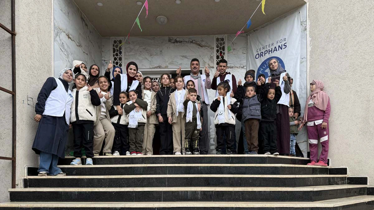 Les enfants de la Maison des orphelins et l'équipe qui les accompagne, réunis sur les marches du bâtiment.