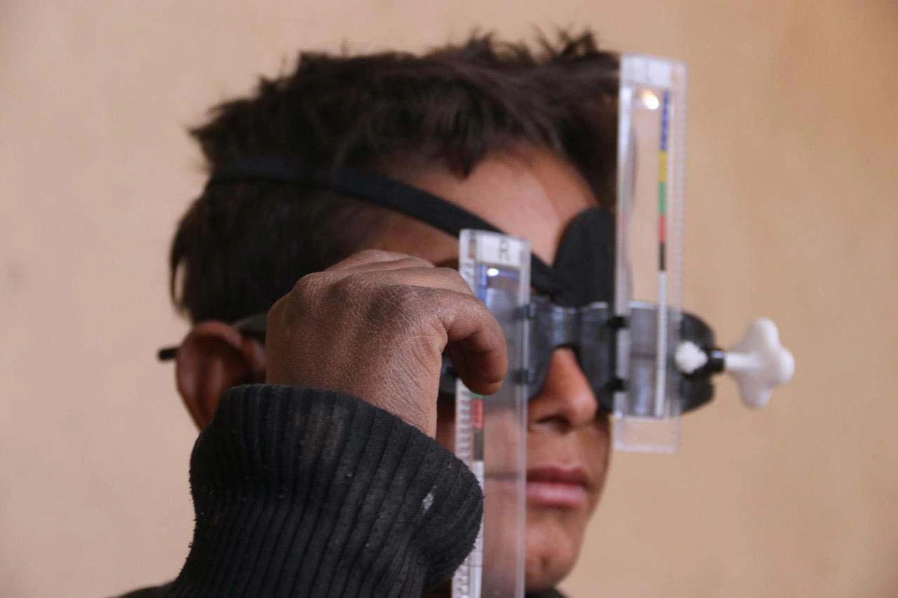 Examen de la vue : un enfant porte une monture d'essai pendant qu'un soignant règle l'écart des verres.