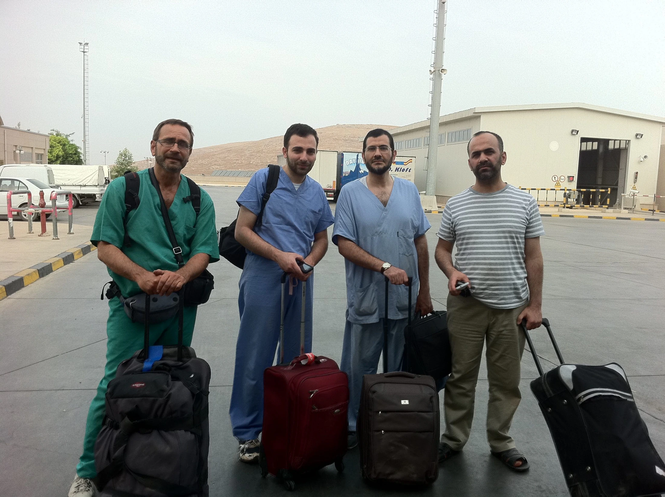 Quatre soignants en tenue médicale, bagages à la main, au départ d'une mission.